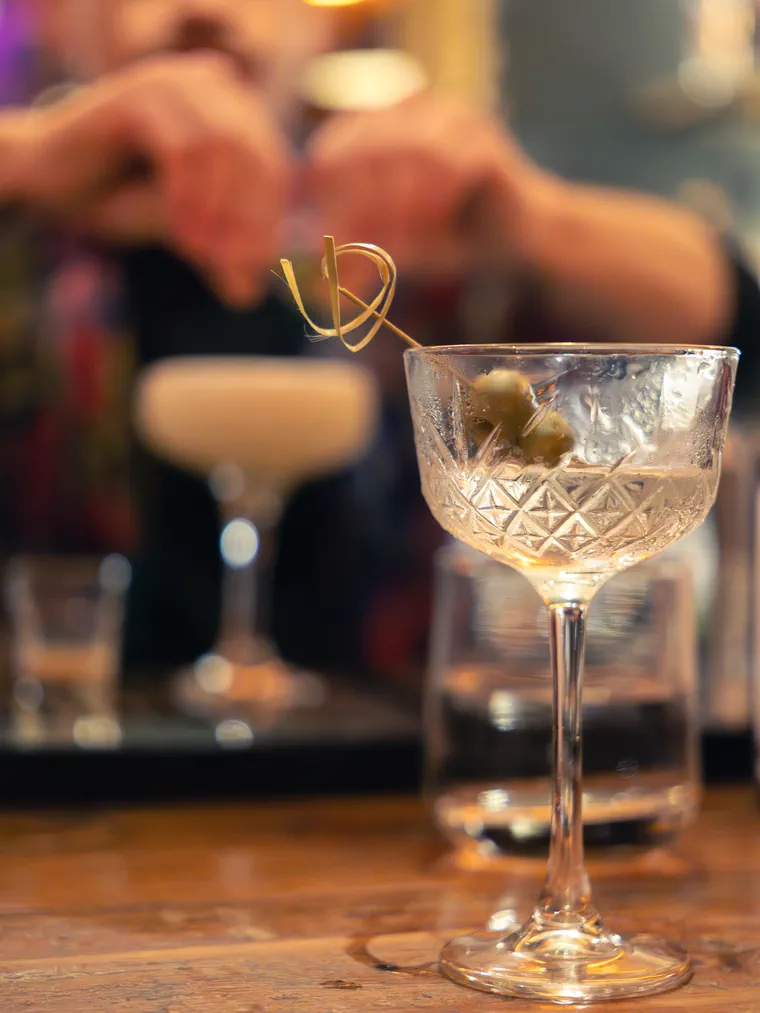 Cóctel en copa coupe con aceitunas sobre la barra de un bar de Valparaíso