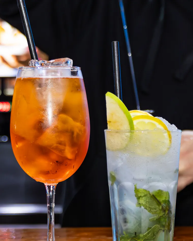 Trago naranjo y vaso alto con menta, hielo molido y rodajas de limón, fotografía gastronómica en Valparaíso