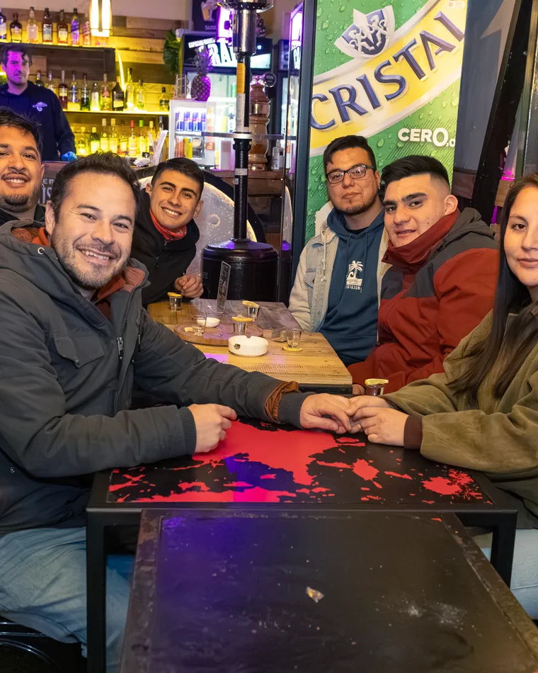 Seis personas posando alrededor de su mesa, cobertura de noche en un bar de Valparaíso