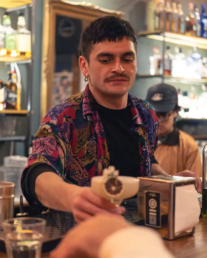 Copa con espuma servida sobre la barra hacia un cliente, cobertura de noche para bares en Valparaíso