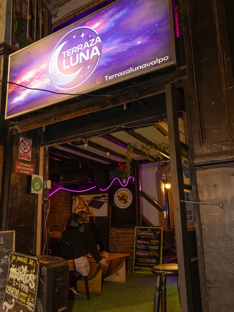 Entrada iluminada de un bar de Valparaíso con su letrero de neón, contenido mensual para negocios