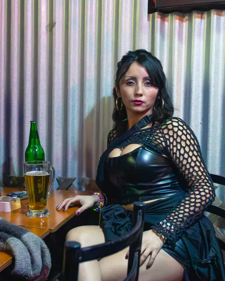 Mujer sentada a una mesa con vaso de cerveza y botella verde en un local, pack mensual de contenido