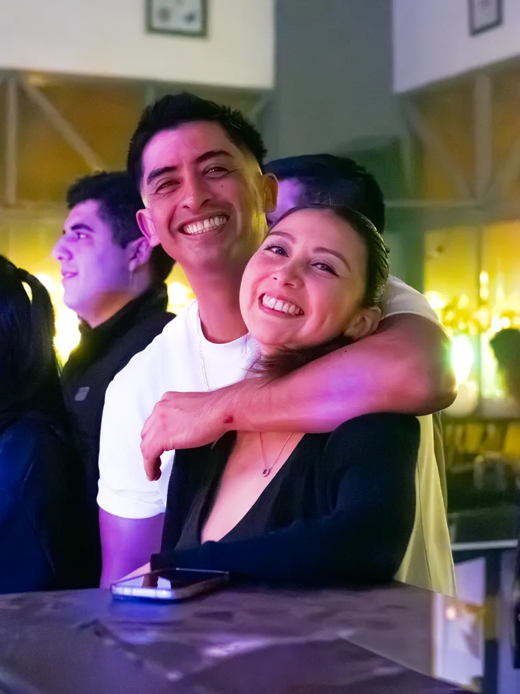 Pareja abrazada y sonriendo junto a la barra en un evento de noche, cobertura de eventos en la región de Valparaíso