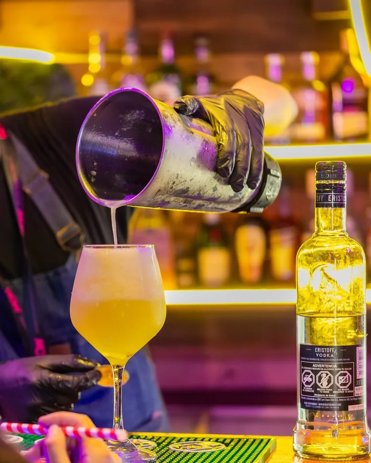 Bartender sirviendo un cóctel amarillo en copa, fotografía gastronómica en un bar de Valparaíso