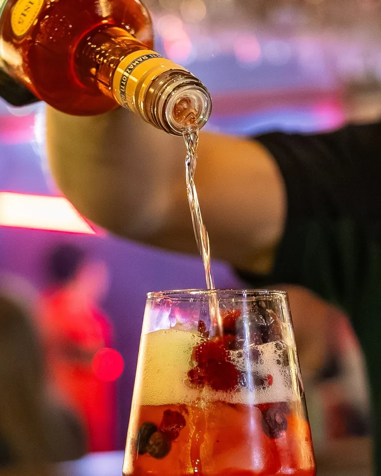 Trago sirviéndose sobre frutos rojos en la copa, cuadro del video de una noche de bar