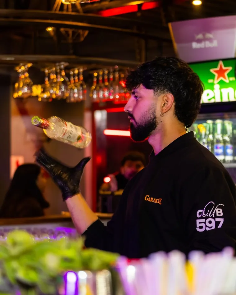 Bartender sirviendo tras la barra iluminada de un bar de Valparaíso, cobertura de noche