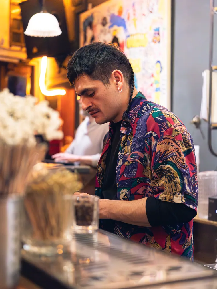 Bartender de camisa estampada tras la barra, en la cobertura fotográfica de un bar de Valparaíso