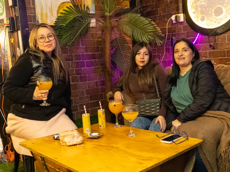 Grupo de personas con sus tragos en la mesa de un bar de Valparaíso, cobertura de noche
