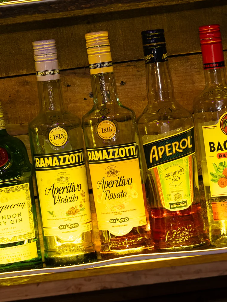 Estante iluminado con botellas de aperitivo en la barra de un bar de Valparaíso