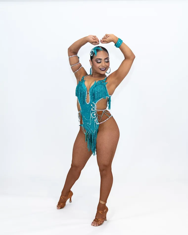 Bailarina con traje turquesa de flecos posa en fondo blanco, sesión de fotografía de danza en estudio