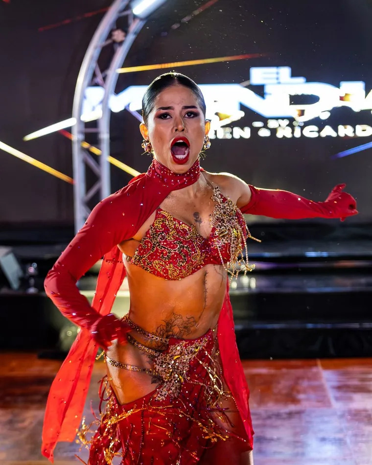 Bailarina de rojo y dorado en pleno número sobre el escenario, cobertura de fotografía de danza