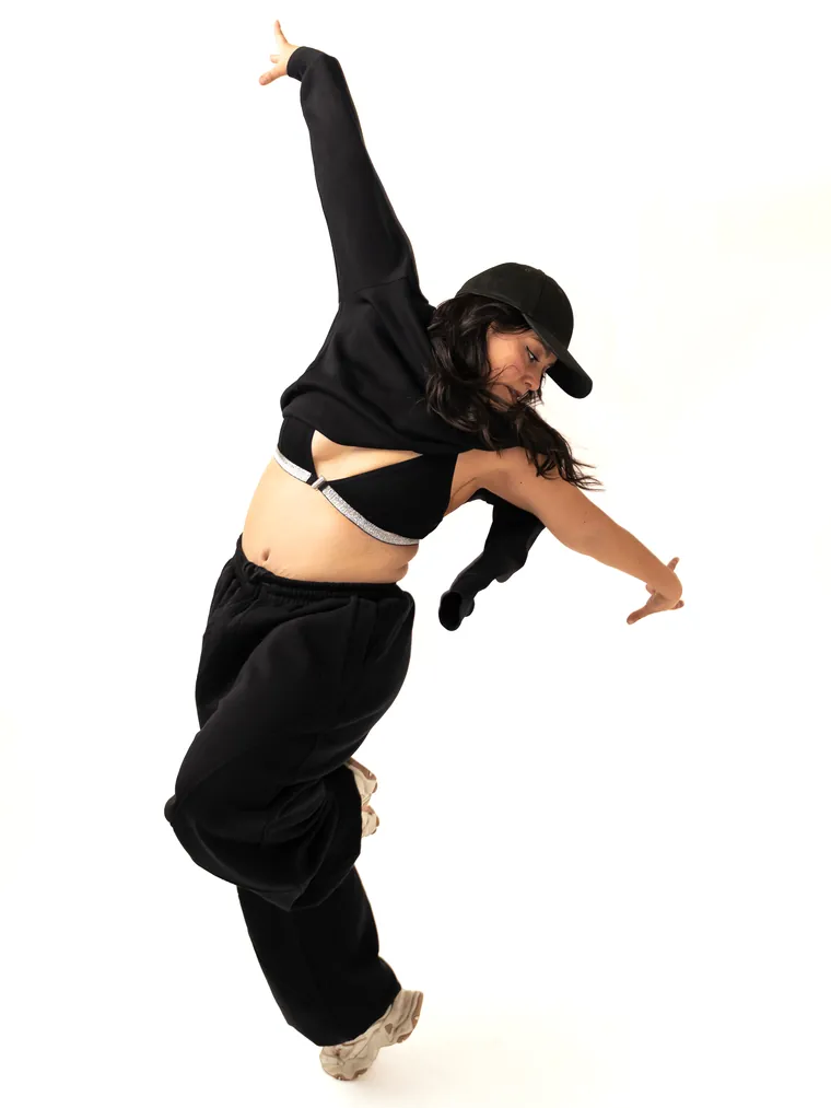 Bailarina urbana en pleno movimiento, apoyada en un pie sobre fondo blanco, fotografía de danza