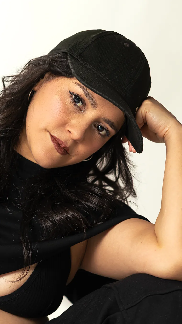 Retrato cercano de bailarina urbana con jockey negro mirando a cámara, fotografía de danza en estudio