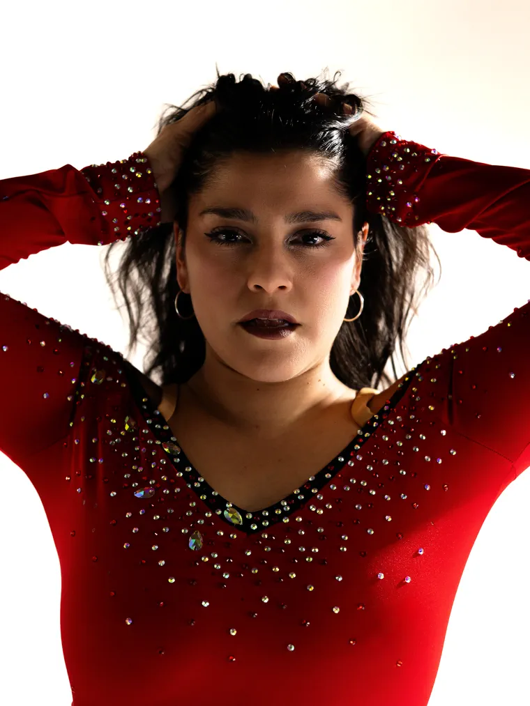 Bailarina de vestido rojo con pedrería y las manos en el pelo, fotografía de danza en estudio