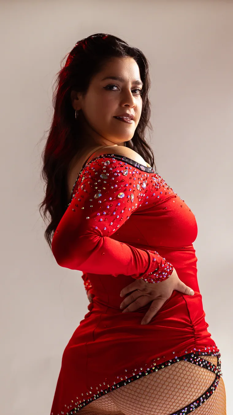 Bailarina de vestido rojo de perfil con la mano en la cintura, fotografía de danza en estudio