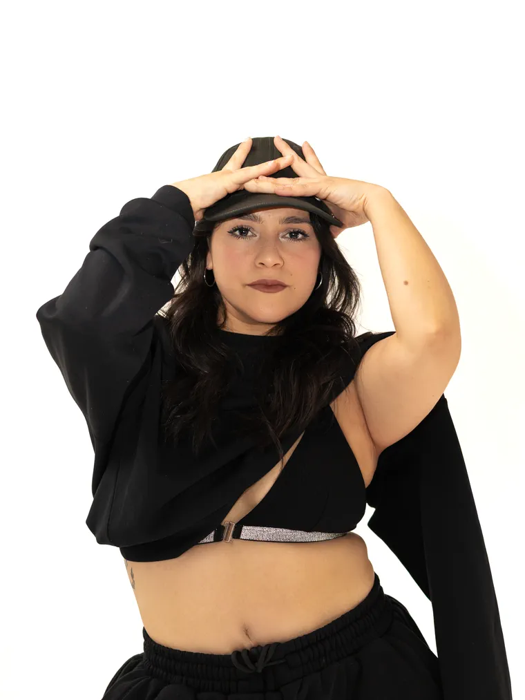 Bailarina urbana con la mano en la cabeza y top negro, fotografía de danza en estudio