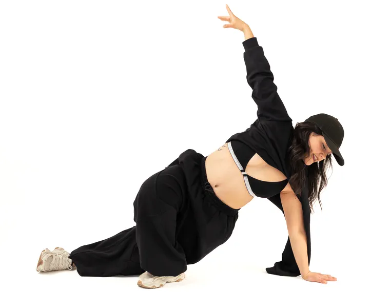 Bailarina urbana apoyada en el suelo en pleno movimiento, fotografía de danza en estudio