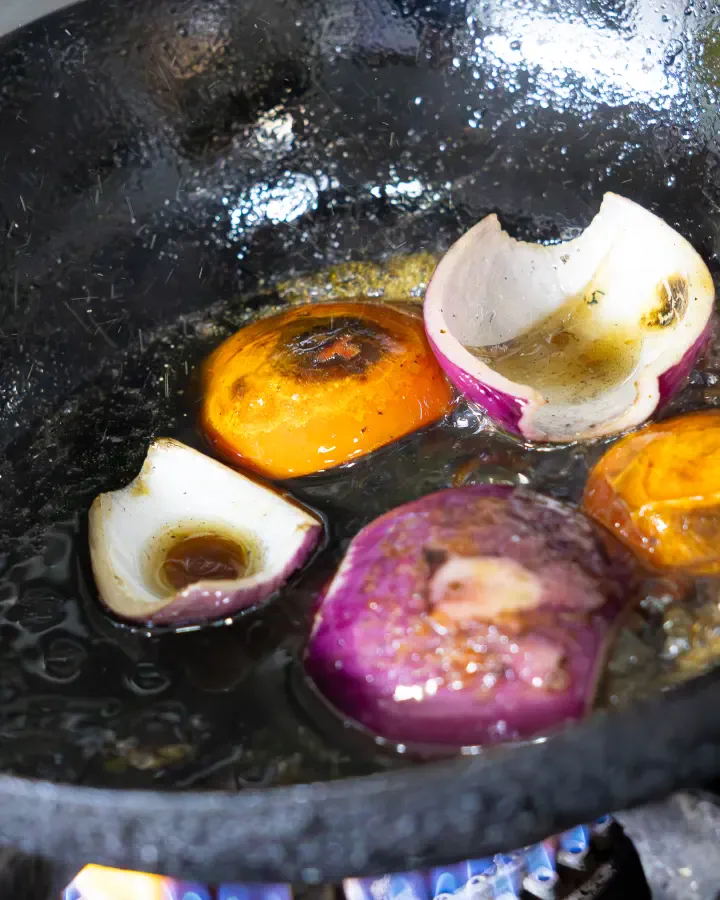Cebolla morada y tomates dorándose en un sartén sobre la llama, fotografía gastronómica en Valparaíso