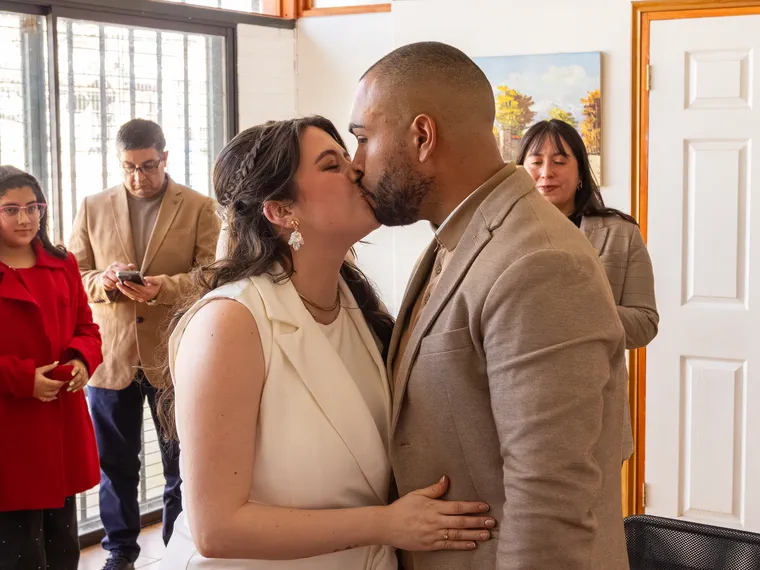 Los novios se besan al terminar la ceremonia civil, con los invitados alrededor