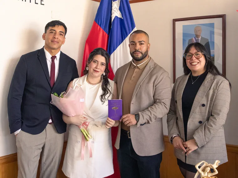 Los novios y sus testigos posan junto a la bandera de Chile después de firmar