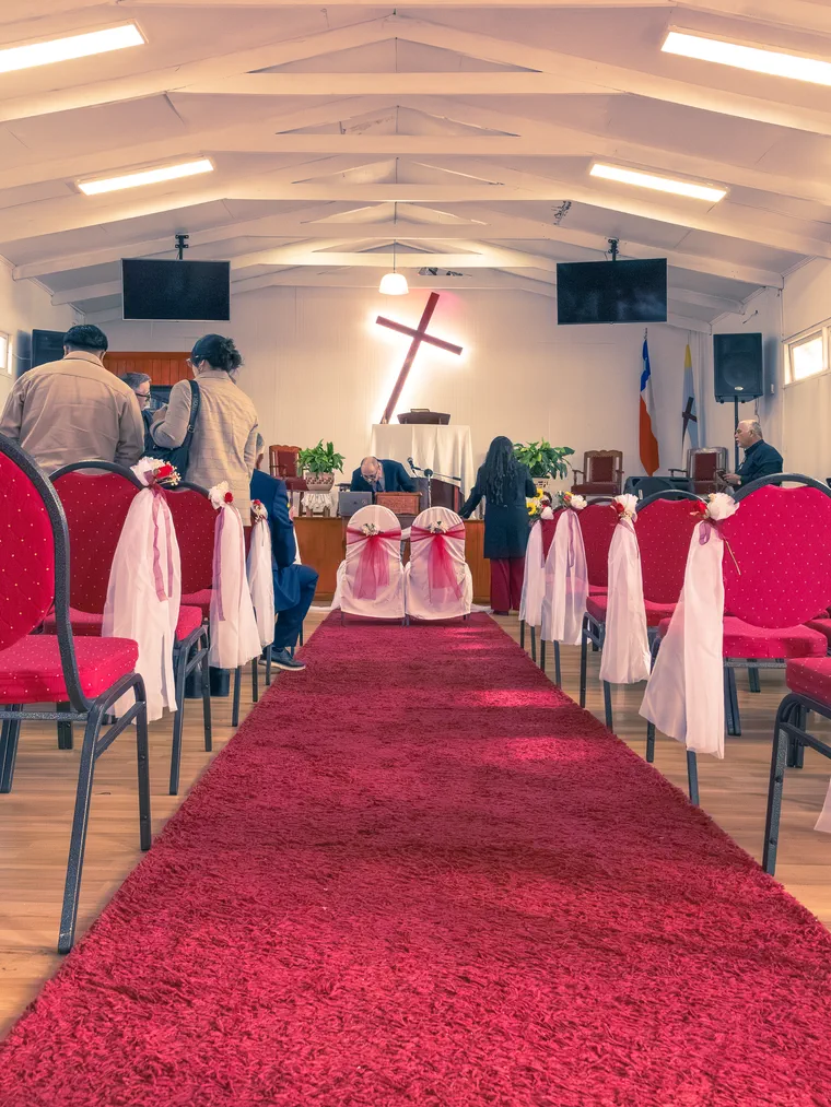 Pasillo de la iglesia con alfombra roja y sillas decoradas antes de la ceremonia de matrimonio