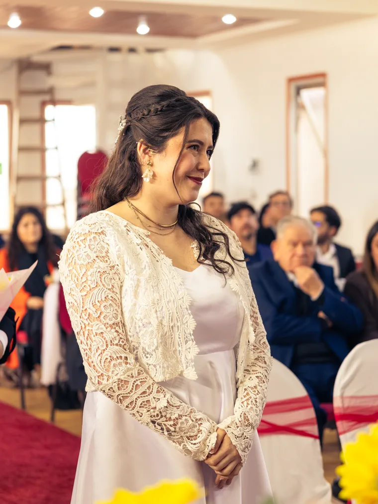 La novia de pie con vestido de encaje mira hacia el altar durante su matrimonio
