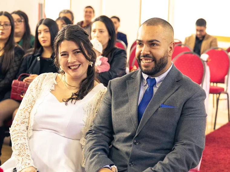 Los novios sentados y sonriendo durante la ceremonia religiosa de su matrimonio