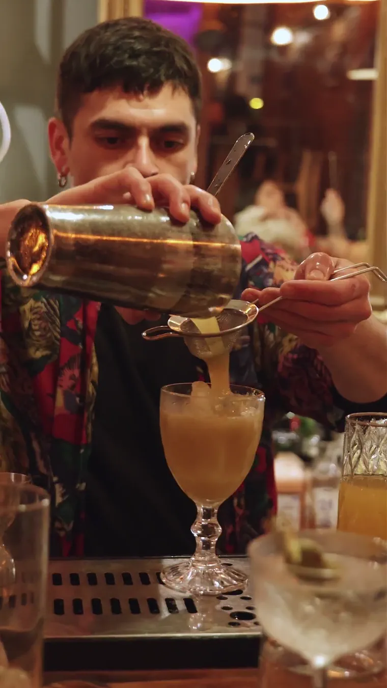 Bartender sirviendo un trago con la cara entera a la vista, cuadro del recap de una noche en un bar