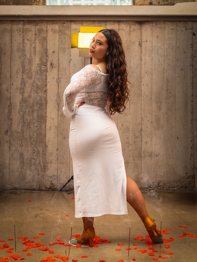 Artista de vestido blanco posa entre muros de concreto en una sesión en locación en Valparaíso