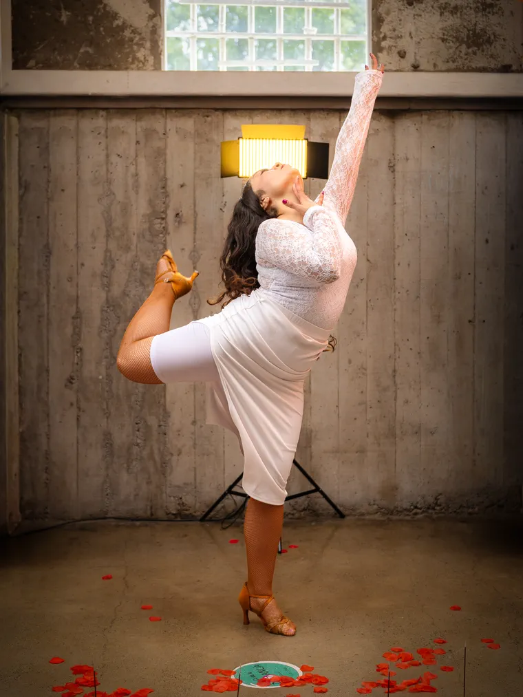 Artista de vestido blanco con la pierna en alto en una pose de baile, sesión en locación en Valparaíso