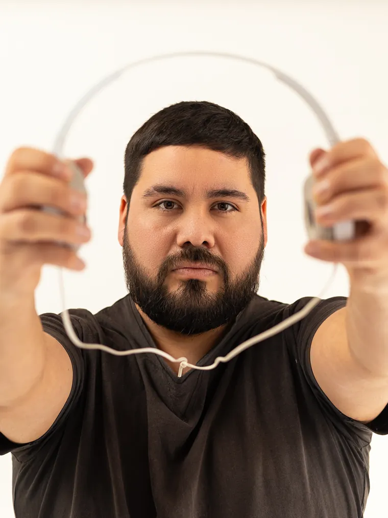 Retrato de marca personal en estudio: hombre estira los brazos y enmarca su cara con los audífonos