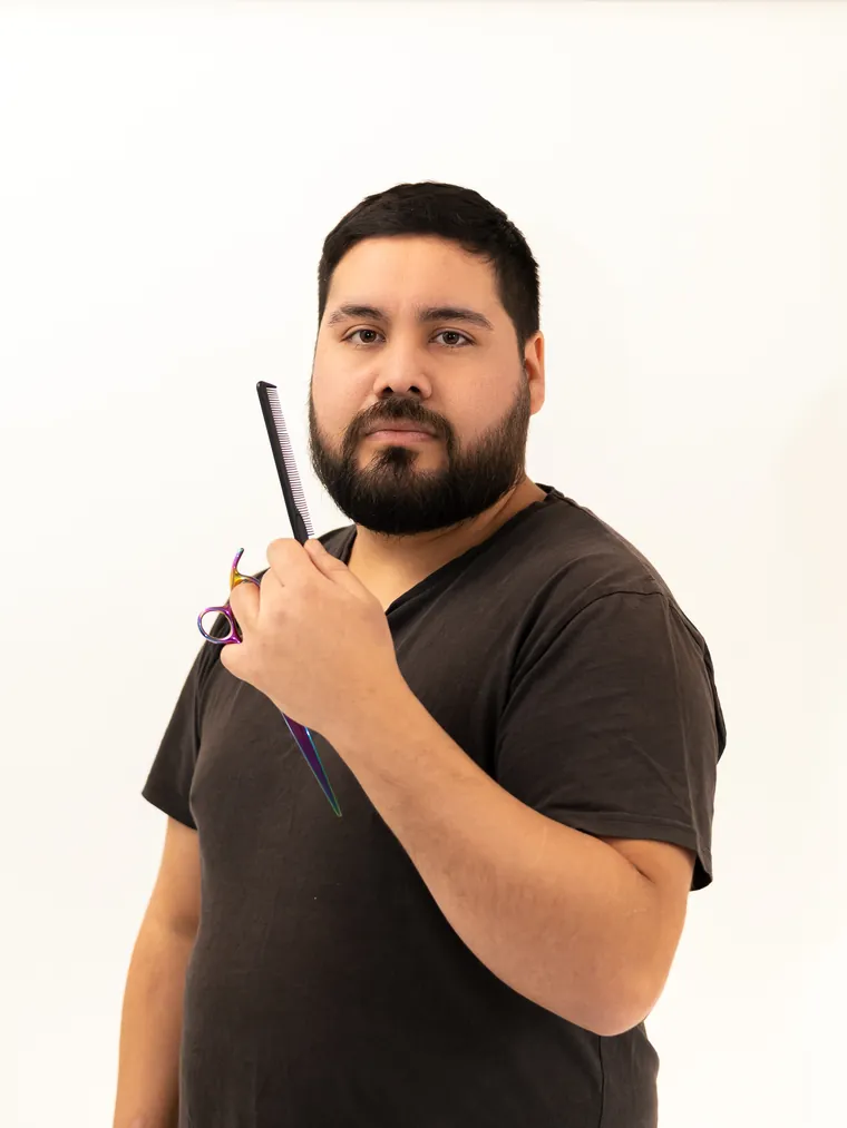 Sesión de marca personal en estudio: hombre alza una peineta negra y tijeras de peluquería de colores