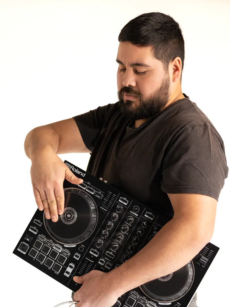 Sesión de marca personal: hombre sostiene su controlador de dj apoyado en el brazo, en estudio
