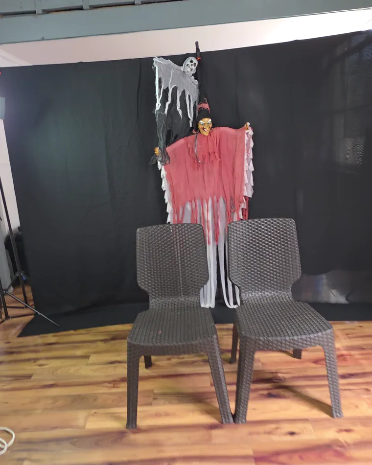 Set de Halloween armado en el estudio de Valparaíso: fondo negro, una bruja, un esqueleto y dos sillas