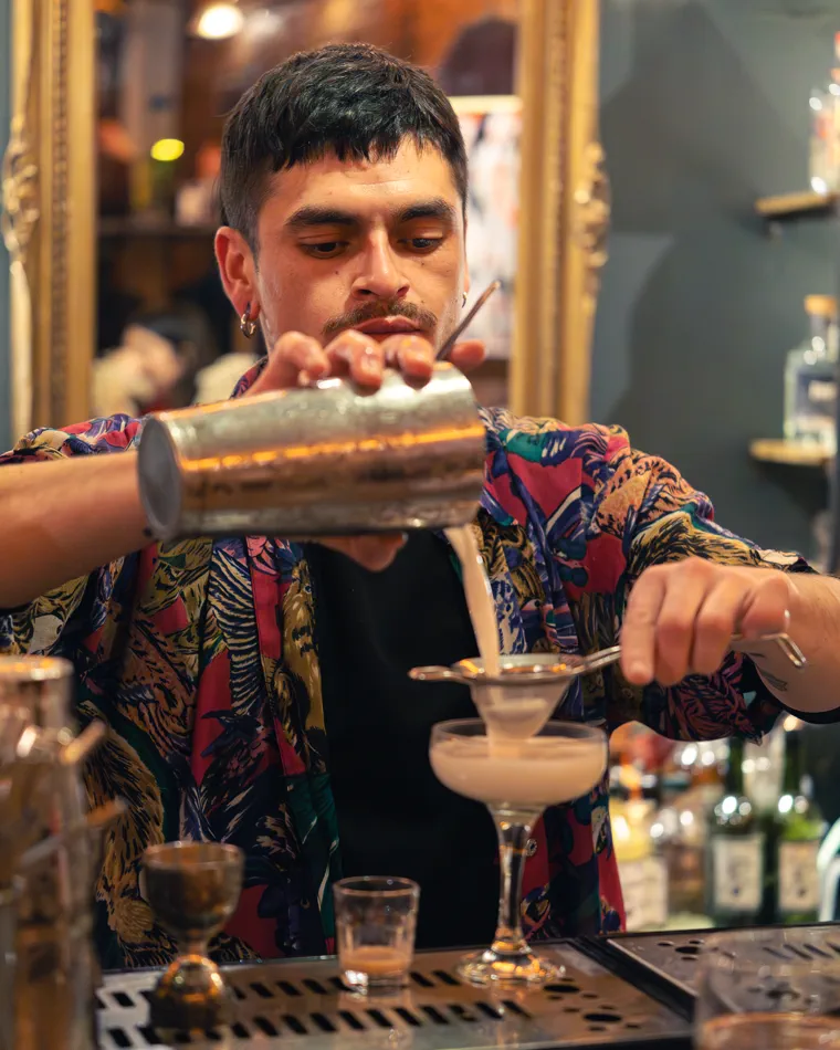 Barman cuela un trago espumoso en la copa, cuadro del reel de una noche en un bar de Valparaíso
